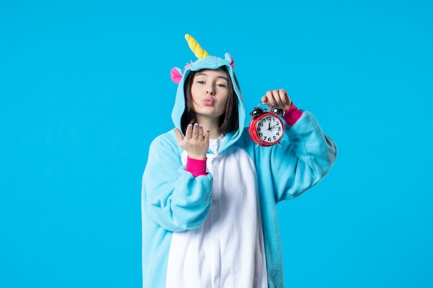 front view young female in pajama party holding red clocks on blue background late time dream rest bed nightmare fun sleep game woman night kiss