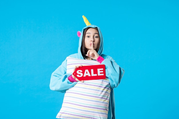Photo front view young female in pajama party holding sale writing and pillow on blue background nightmare bed dream late rest night friends fun color