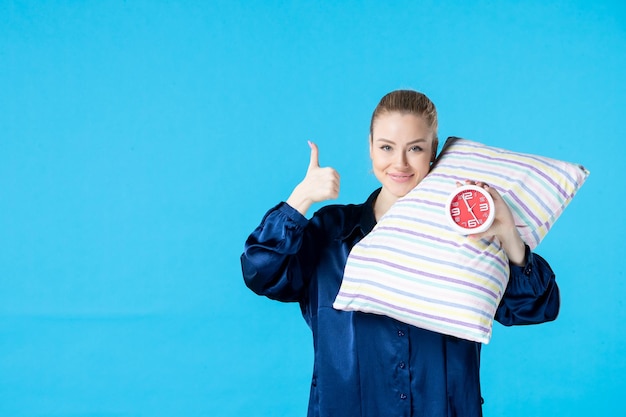 front view young female in pajamas holding clocks and pillow on blue background tired bed night rest sleep nightmare woman party dream