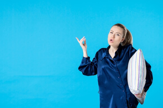 front view young female in pajamas holding pillow on blue background nightmare party color yawn sleep night rest woman bed