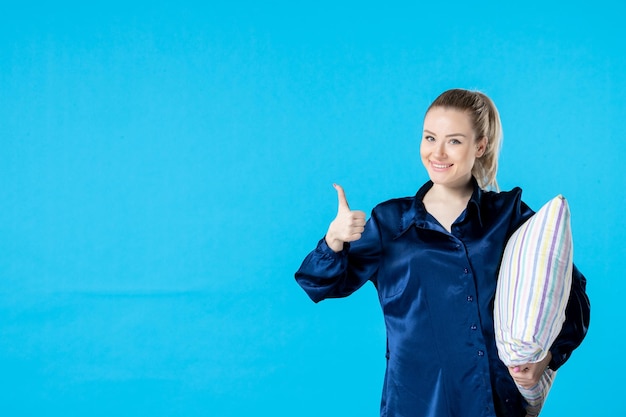 front view young female in pajamas holding pillow on blue background nightmare party woman color bed dream yawn sleep night rest smile