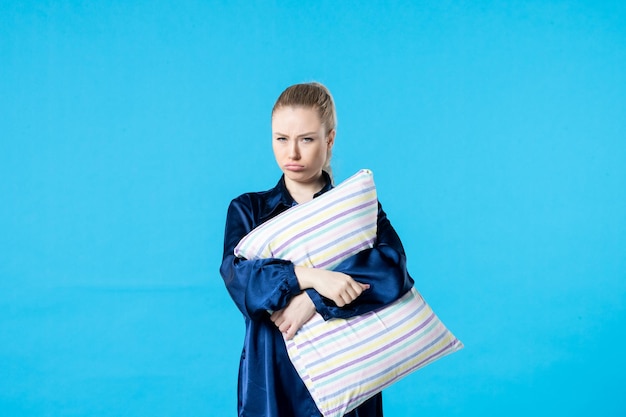 front view young female in pajamas holding pillow on blue background sleep nightmare party color dream yawn night woman bed