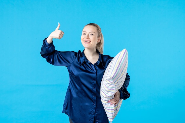 front view young female in pajamas holding pillow on blue background sleep nightmare party dream smile yawn night rest woman bed color