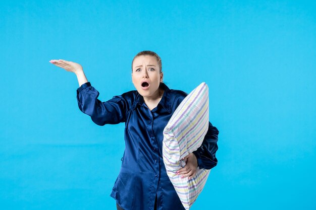 front view young female in pajamas holding pillow on blue background sleep nightmare party dream yawn rest woman bed night tired