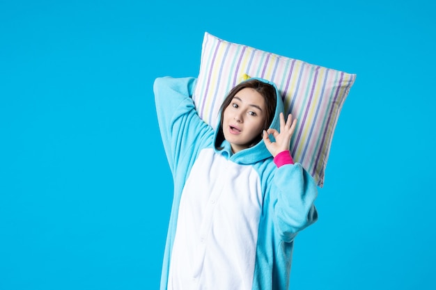вид спереди молодая женщина в пижаме для пижамной вечеринки держит подушку на синем фоне кровать женщина отдыхает поздно весело сон игра сон ночь