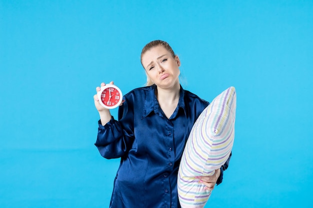 front view young female in pajamas with clock and pillow on blue background night party rest sleep tired late dream bed nightmare