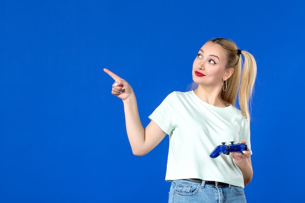 Vista frontale giovane femmina che gioca al videogioco con gamepad su sfondo blu giocatore gioioso video gioventù vincente internet divano adulto virtuale online