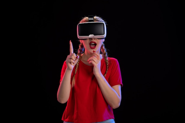 Front view of young female playing vr on dark wall