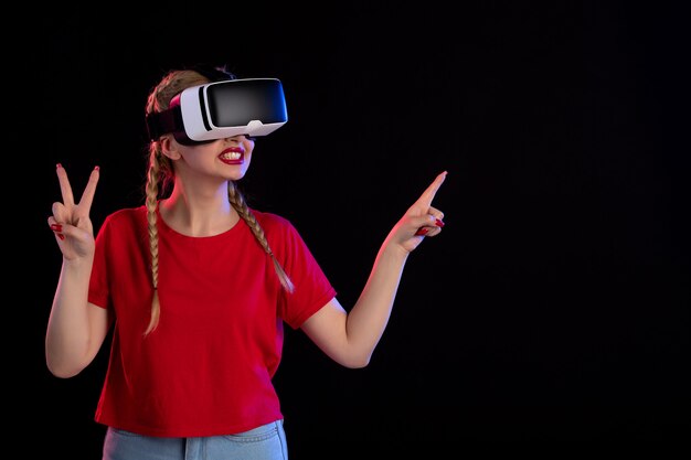 Front view of young female playing vr on dark wall