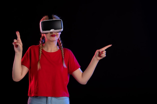 Front view of young female playing vr on dark wall