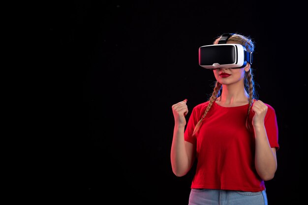 Front view of young female playing vr on the dark wall