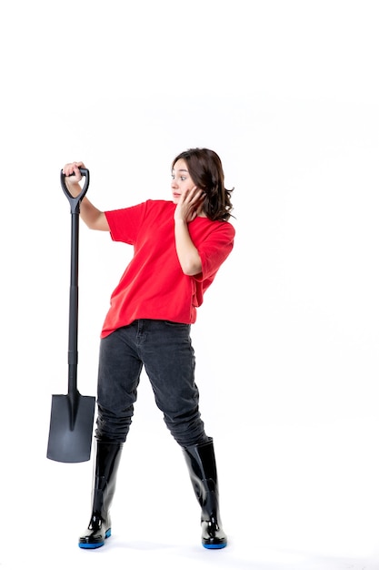 front view young female in red shirt holding black shovel on white background color woman emotion digging soil cemetery ground