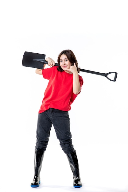 front view young female in red shirt holding black shovel on white background woman clean ground soil digging cemetery color emotions