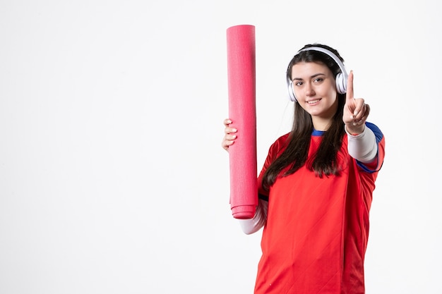 Front view young female in sport clothes holding yoga mat