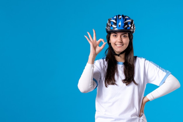 Front view young female in sport clothes with helmet on blue wall