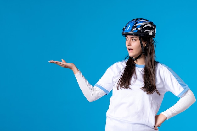 Front view young female in sport clothes with helmet on blue wall