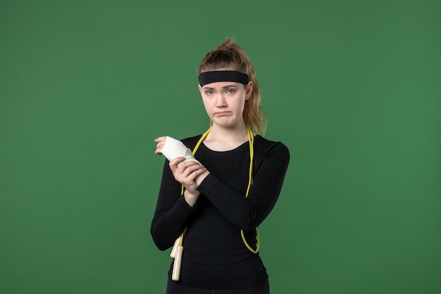 Front view young female with bandage around her hurt arm on green background sport athlete pain health injury woman workout body colors