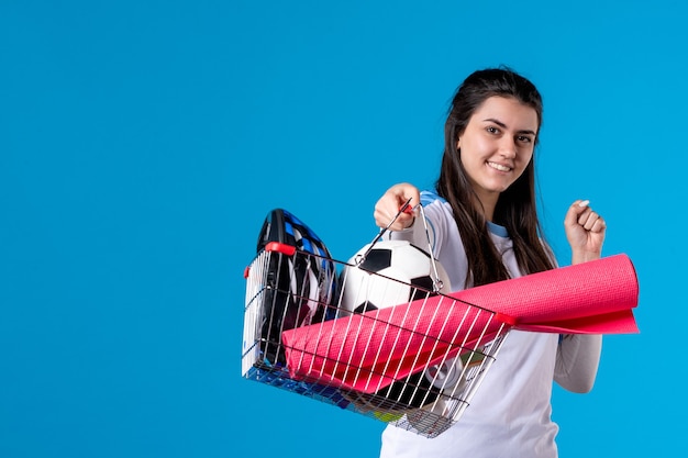 Giovane femmina di vista frontale con il canestro dopo lo shopping di sport sulla parete blu