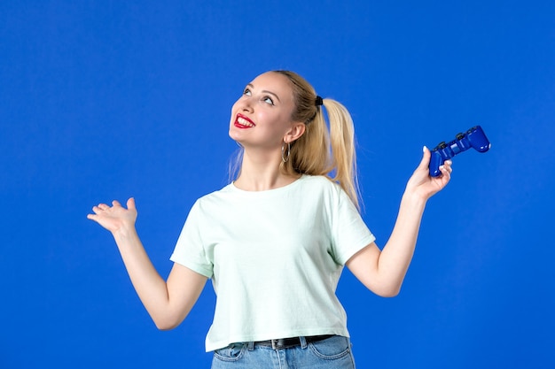 正面図青い背景にゲームパッドを持つ若い女性うれしそうなプレーヤー大人のソファを獲得インターネット仮想青年オンライン