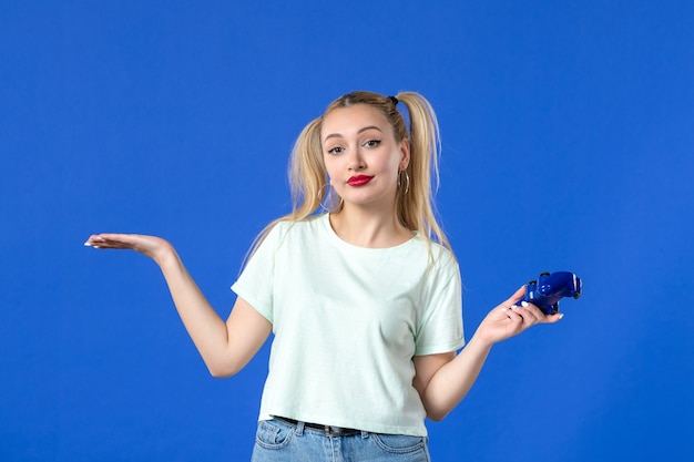 正面図青の背景にゲームパッドを持つ若い女性ビデオ大人のプレーヤー仮想ジョイスティック勝利オンライン青年
