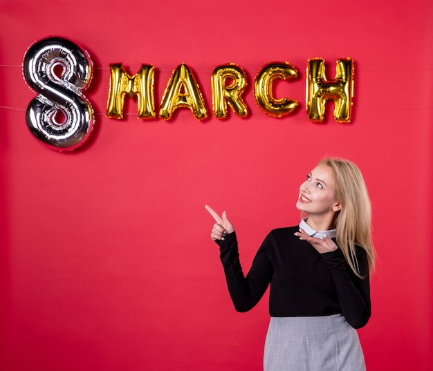 front view young female with march decoration on red background sensual equality passion salon love womans day feminine luxurious holiday