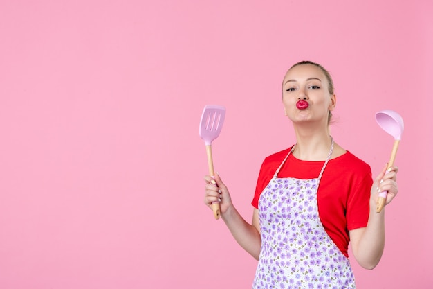 Photo front view young housewife holding cutlery on pink wall