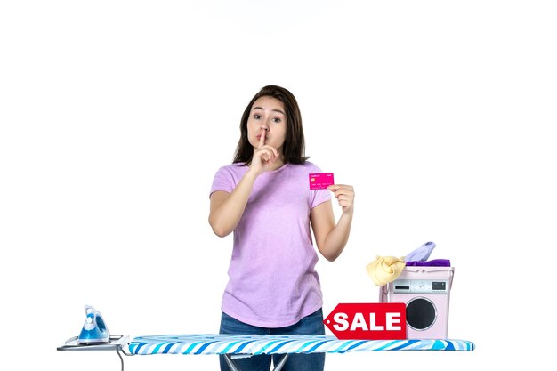 front view young housewife holding pink bank card asking to be silent on white background color laundry work shopping housework sale iron money