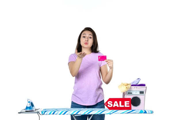 front view young housewife holding pink bank card and sending kisses on white background color laundry work clothes shopping housework sale iron money