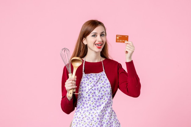 front view young housewife holding whisk and bank card on pink background pie sweet food cuisine cooking kitchen woman color cakes