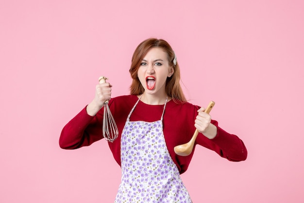 front view young housewife holding whisk and wooden spoon on pink background cooking uniform horizontal cuisine profession woman cake