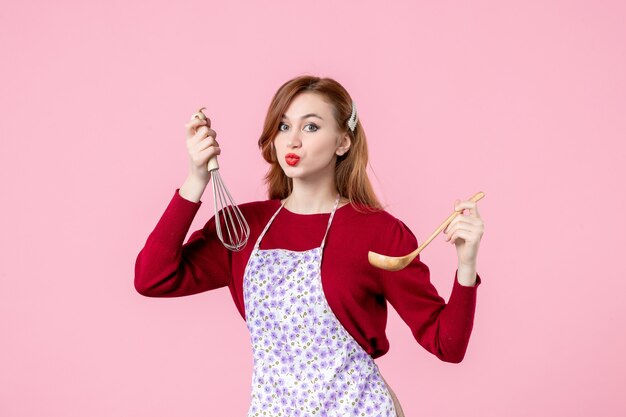 front view young housewife holding whisk and wooden spoon on pink background cuisine cooking uniform horizontal woman pie cake