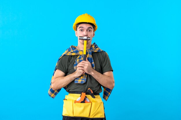 正面図青の背景にハンマーを保持している若い男性ビルダー労働者の家コンストラクターフラットジョブ建物アーキテクチャ