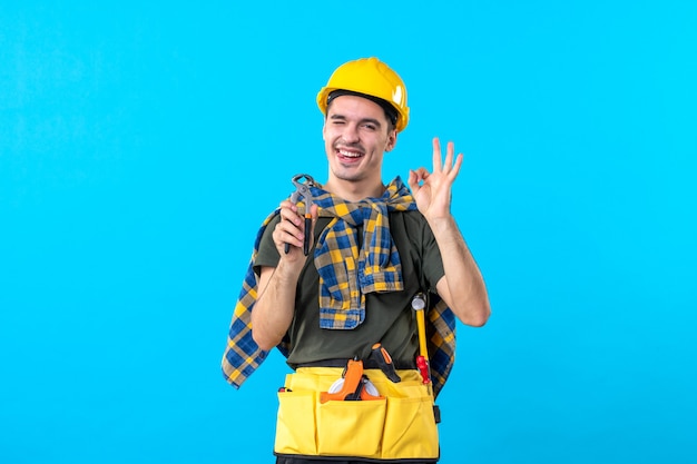 front view young male builder with different tools on the blue background flat job worker constructor building architecture house