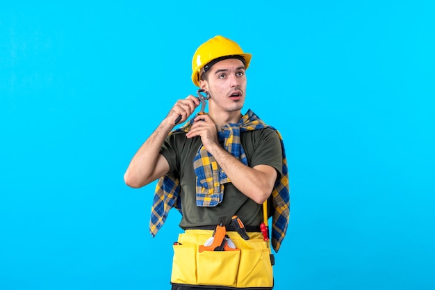 front view young male builder with different tools on blue background flat job worker constructor building architecture