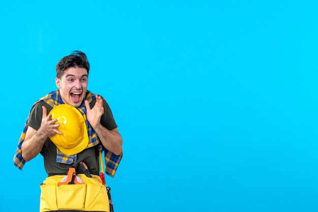 front view young male builder with yellow helmet on blue background constructor architecture building color tool flat worker house