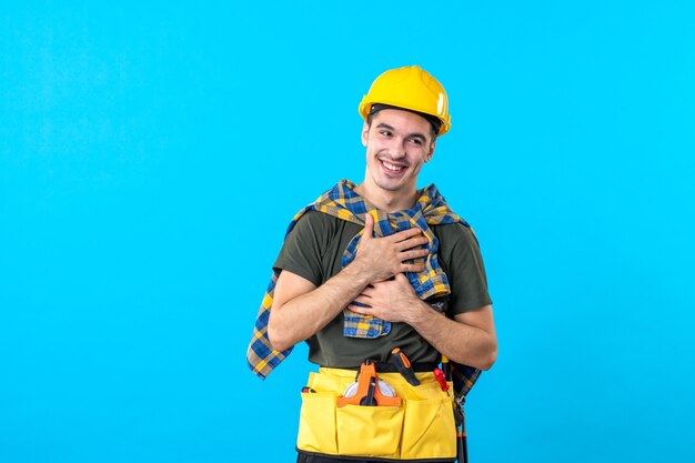 front view young male builder in yellow helmet smiling on blue background color flat constructor architecture tool building worker