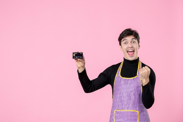 Giovane maschio di vista frontale in capo che tiene la carta di credito su sfondo rosa orizzontale lavoratore colore uniforme lavoro cucina professione capo Foto Premium
