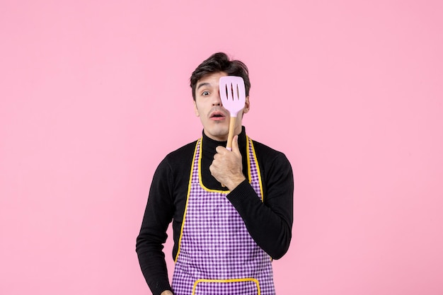 Front view young male in cape holding spoons on pink background profession color meal cooking horizontal work food dough cuisine