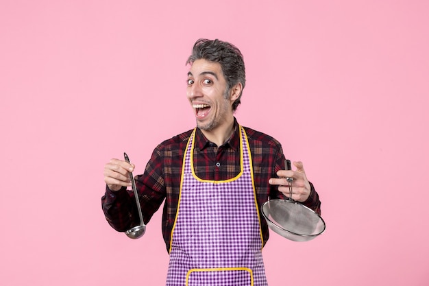 front view young male in cape with sieve and spoon on pink background cuisine kitchen worker food husband horizontal soup profession cook