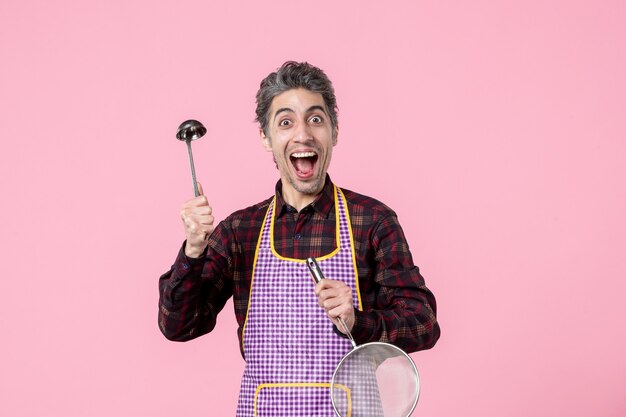 front view young male in cape with sieve and spoon on pink background food cuisine husband horizontal profession uniform kitchen worker cook