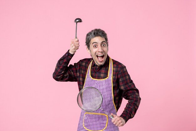 front view young male in cape with sieve and spoon on pink background horizontal food cuisine profession uniform worker husband kitchen