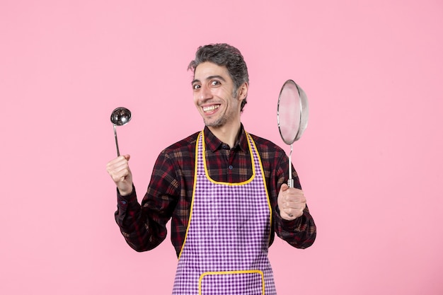 front view young male in cape with sieve and spoon on pink background uniform kitchen horizontal profession husband cuisine worker