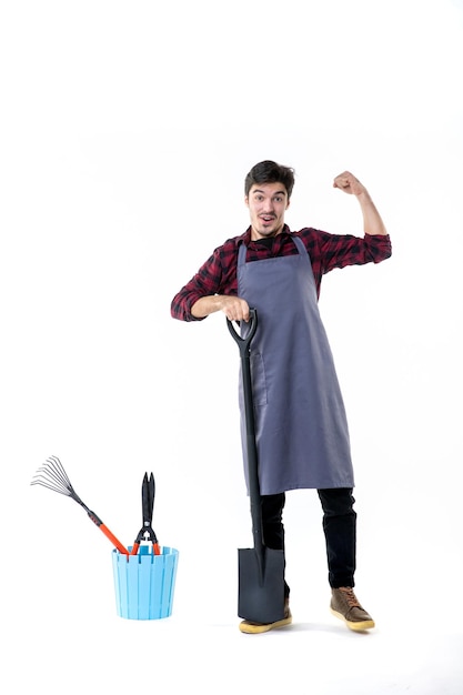 front view young male gardener with black shovel on a white background garden digging uniform work job ground soil flower