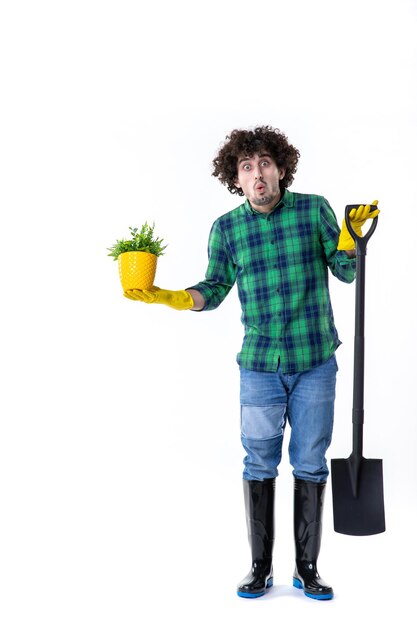 front view young male gardener with shovel and little plant in pot on the white background job uniform tree flower grass field water garden