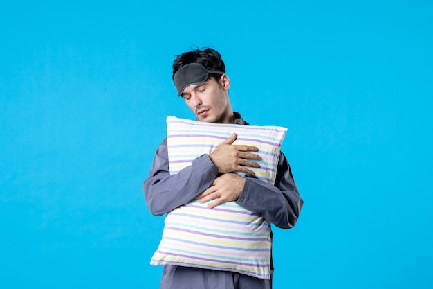 front view young male in his pajamas holding pillow on blue background human dream sleep night color late bed rest nightmare wake tired