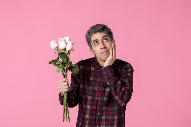 Front view young male holding beautiful pink roses on pink wall