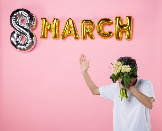 front view young male holding flowers for woman with march decorated pink background sensual feminine womens day emotion holiday party glamour equality