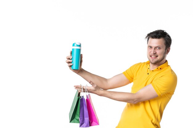 front view young male holding little packages and thermos on white background job color sport human uniform worker shopping water