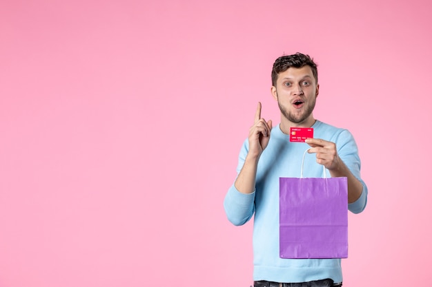 front view young male holding present in purple package and bank card on pink background feminine fun equality womens day march marriage date park love