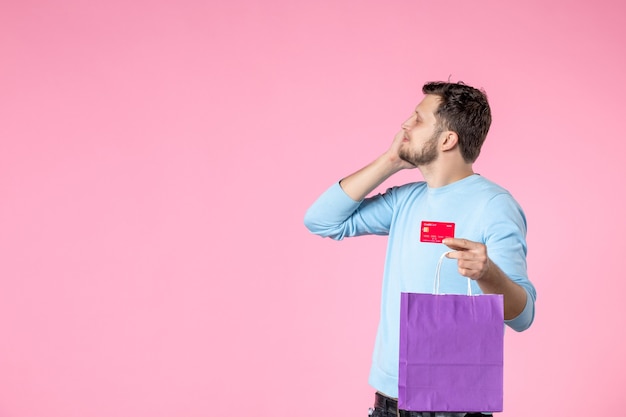 вид спереди молодой мужчина держит подарок в фиолетовой упаковке и банковскую карту на розовом фоне женское чувственное веселье равенство женский день марш дата свадьбы любовь